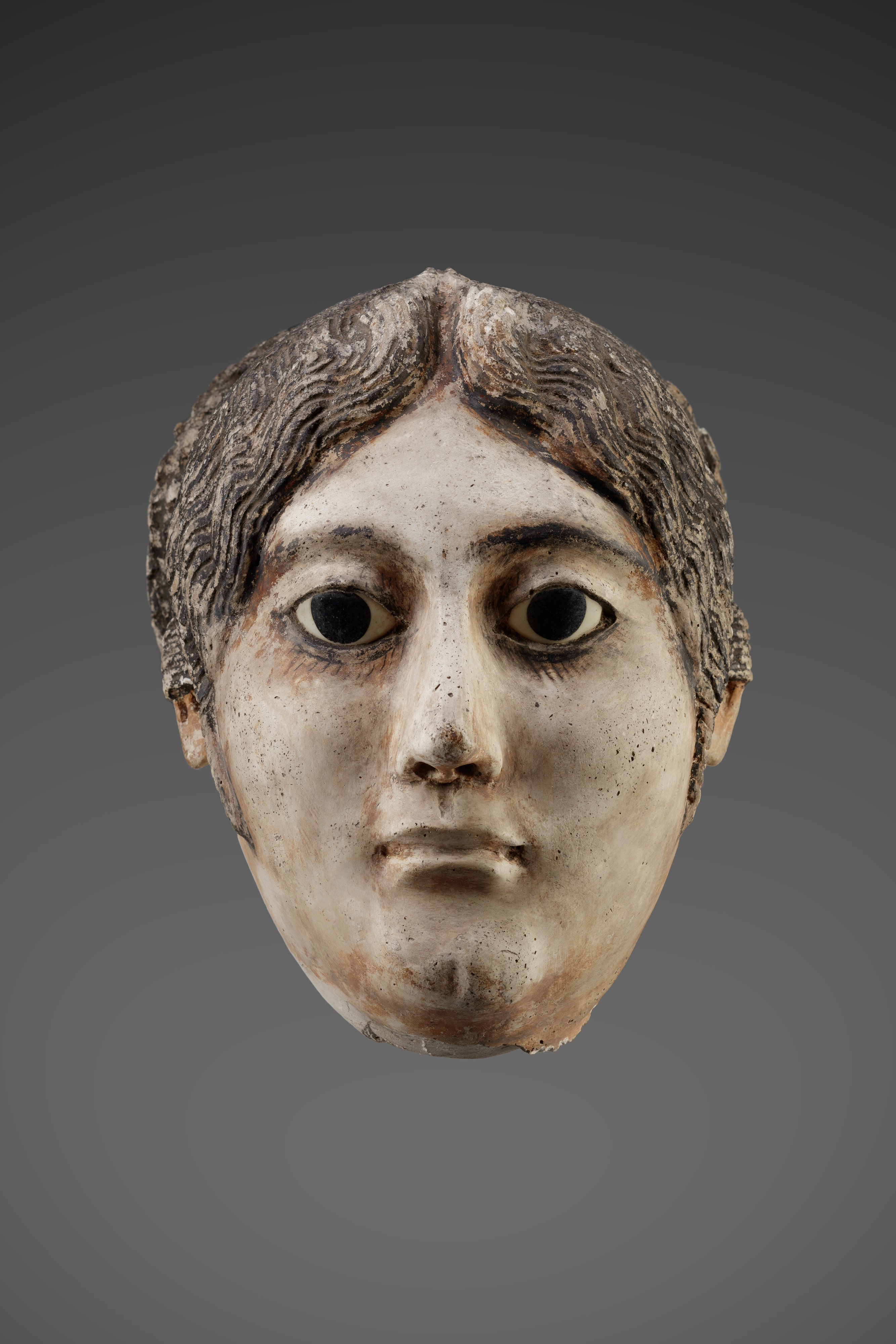Mask of a woman with a large coil of plaited hair