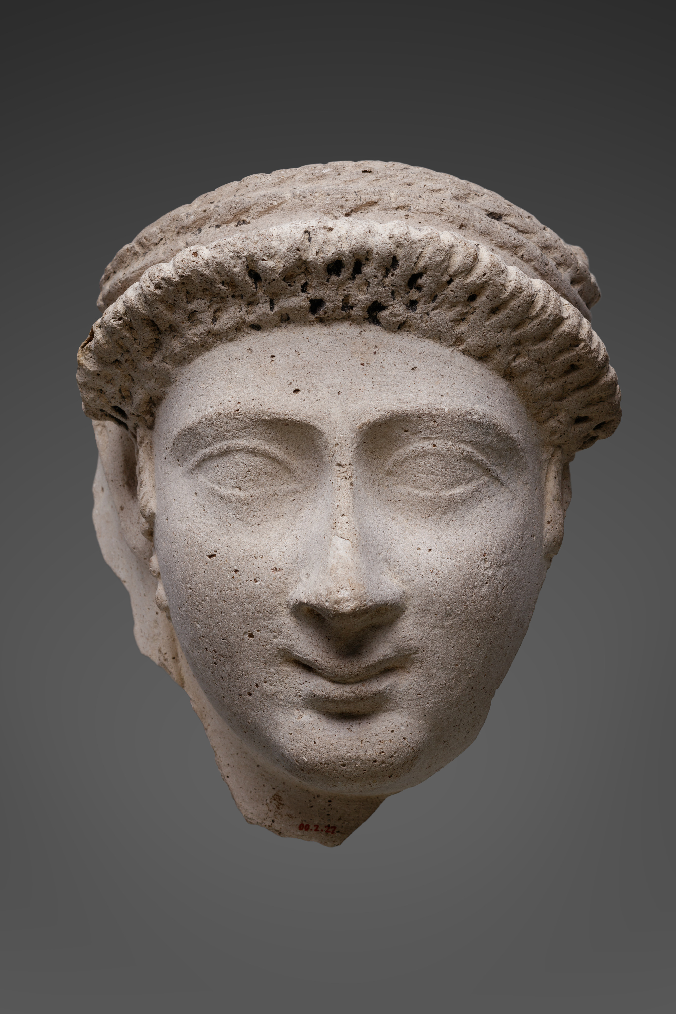 Mask of a woman with an ornate curled bang and loop earrings